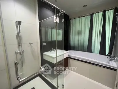 Modern bathroom with glass shower and bathtub, featuring sleek design and natural light.