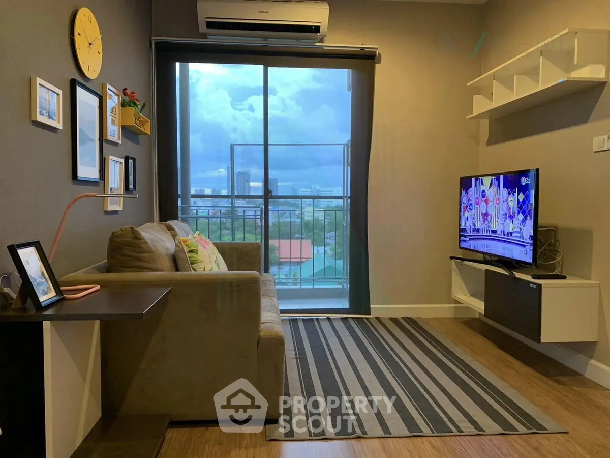 Modern living room with balcony view, stylish decor, and wall-mounted TV in a cozy apartment.