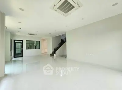 Spacious open-plan living area with modern air conditioning and sleek staircase.