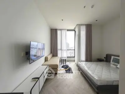 Modern bedroom with minimalist decor, featuring a wall-mounted TV and large window with city view.