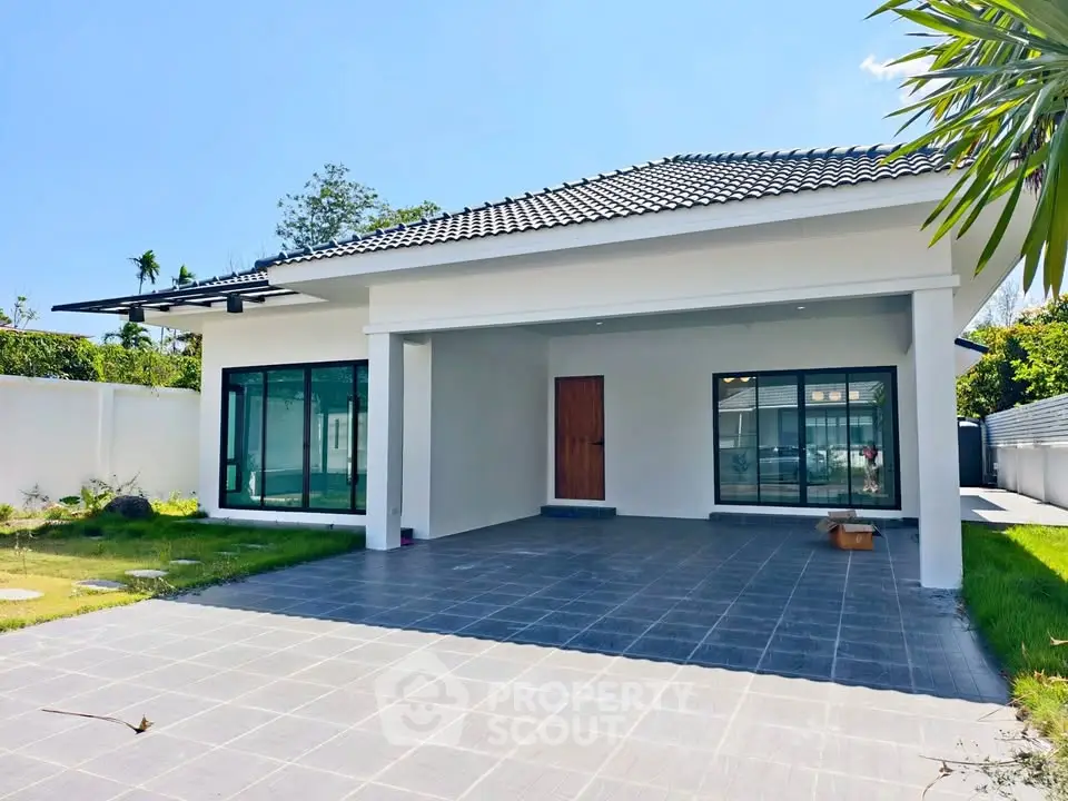 Modern single-story house with spacious driveway and lush greenery, perfect for family living.