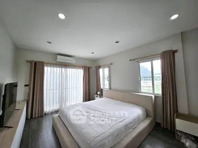 Spacious bedroom with large windows and modern decor, offering a serene and comfortable living space.