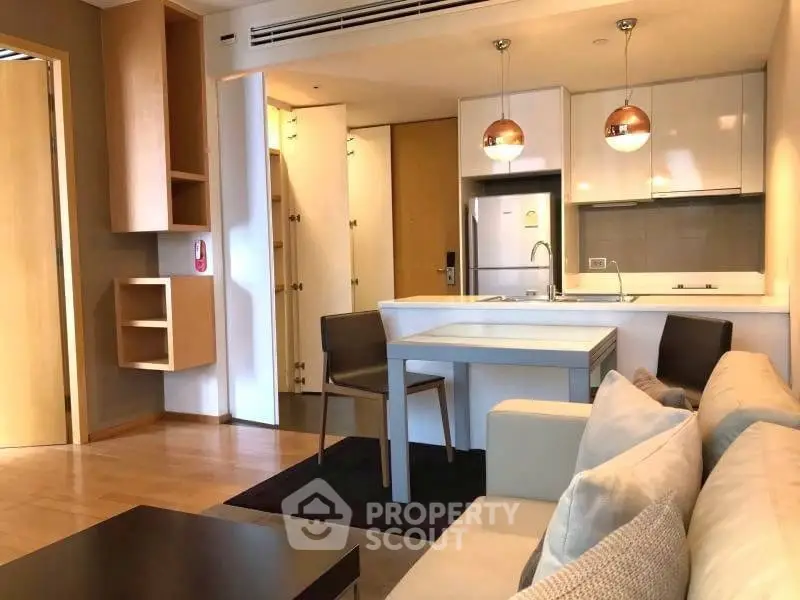 Modern open-layout kitchen and living area with stylish lighting and cozy seating.