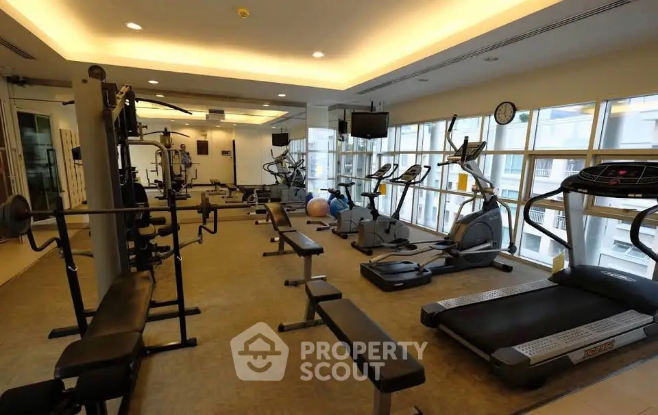 Spacious modern gym with state-of-the-art equipment and large windows for natural light.