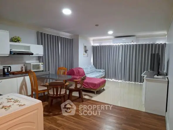 Spacious open-plan living room with modern kitchen and cozy dining area, featuring stylish furniture and ample natural light.
