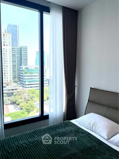 Modern bedroom with large window offering stunning city view in high-rise apartment.