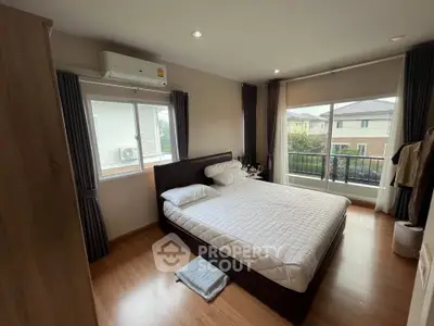 Spacious bedroom with large windows and modern decor in a serene residential area.
