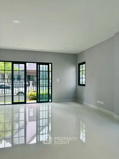 Spacious modern living room with large windows and glossy tiled floor