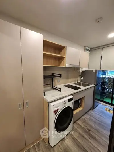 Modern kitchen with washing machine and sleek cabinetry in compact layout