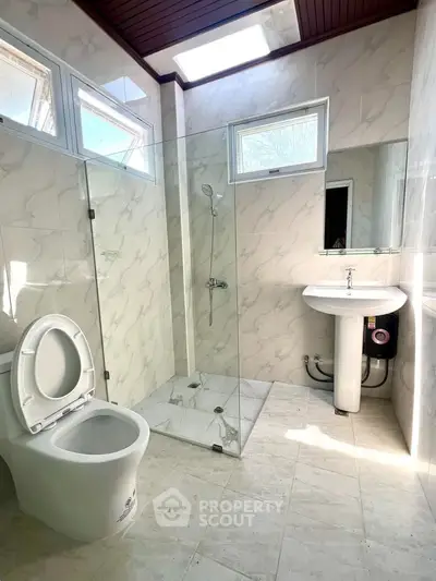 Bright modern bathroom with glass shower and skylight