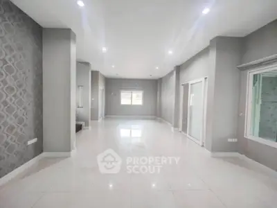 Spacious modern living room with elegant wallpaper and ample natural light.