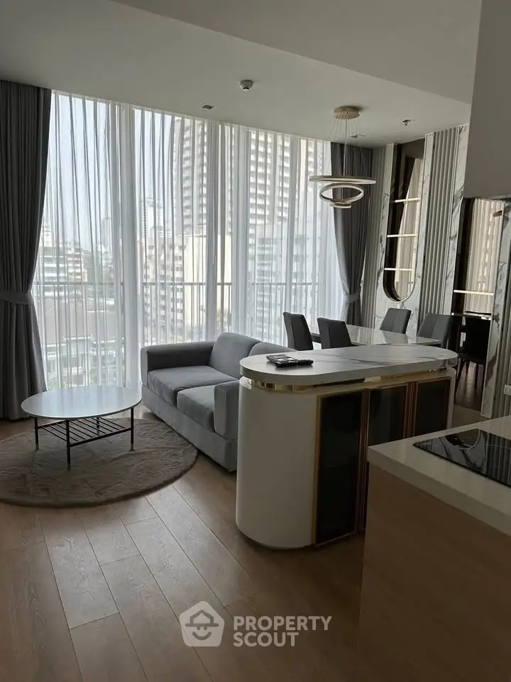 Modern living room with floor-to-ceiling windows and city view, featuring sleek furniture and elegant decor.