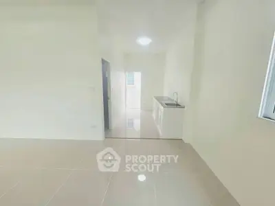 Bright minimalist kitchen with sleek tile flooring and compact sink area.
