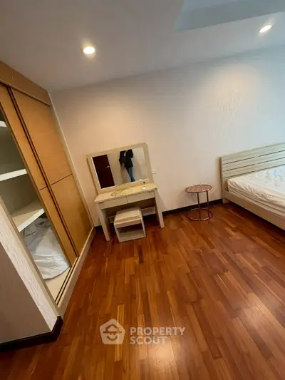 Spacious bedroom with wooden flooring and modern furniture