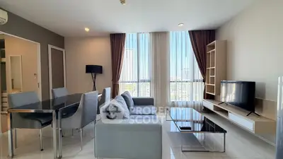 Modern living room with sleek furniture and large windows offering city views.