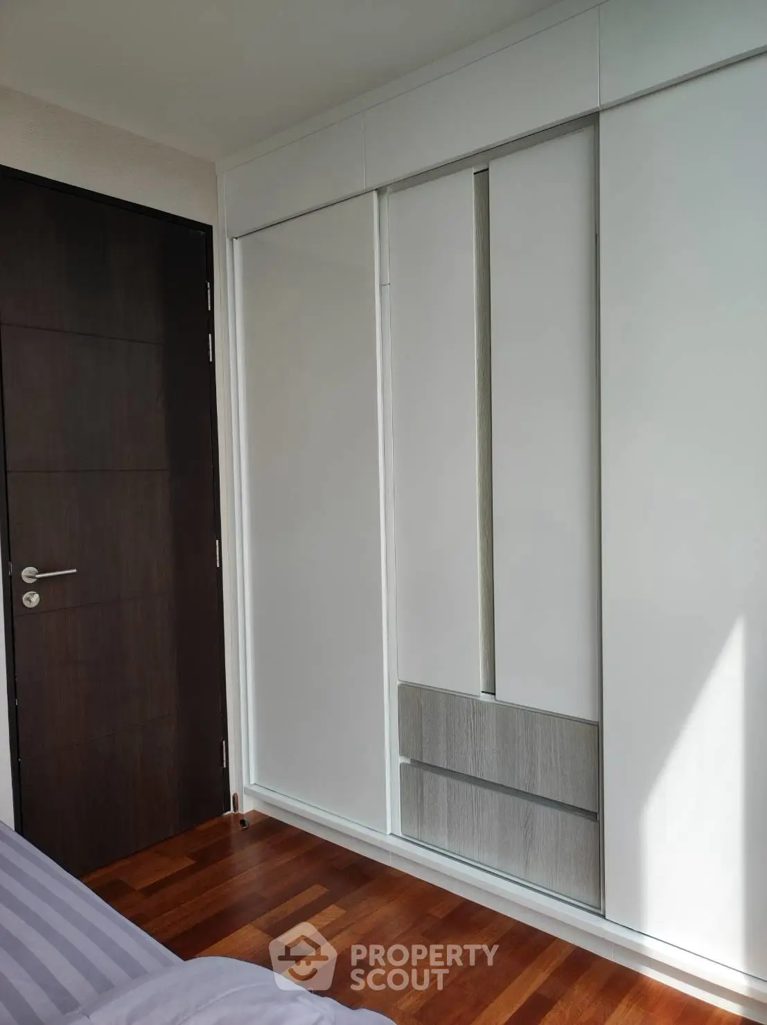 Modern bedroom with sleek built-in wardrobe and wooden flooring