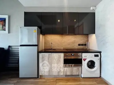 Modern kitchen with sleek cabinets, stainless steel fridge, oven, and washing machine in a compact layout.