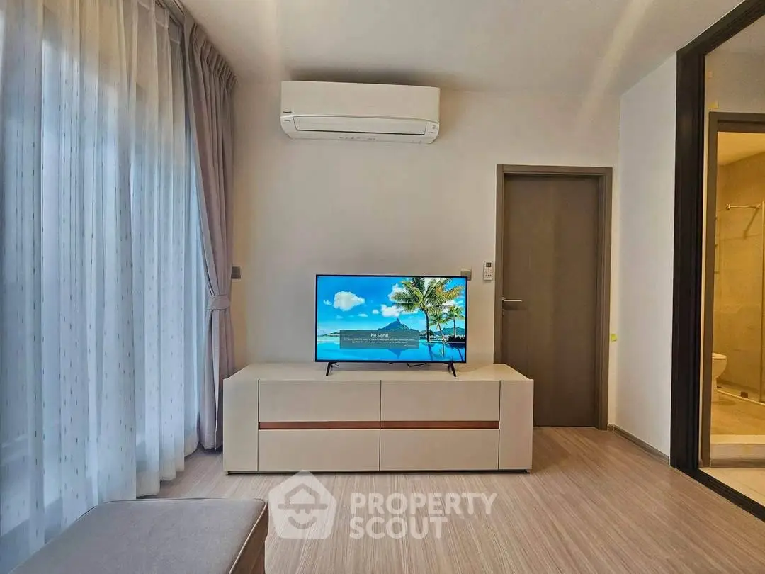 Modern living room with air conditioning and flat-screen TV, featuring elegant curtains and sleek furniture.