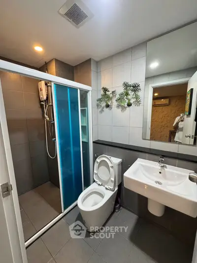 Modern bathroom with glass shower and sleek fixtures in contemporary home.