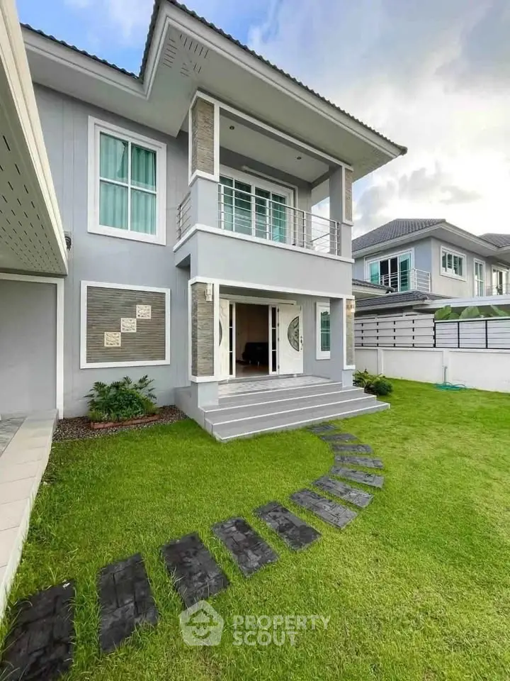 Modern two-story house with a lush green lawn and stylish exterior design.