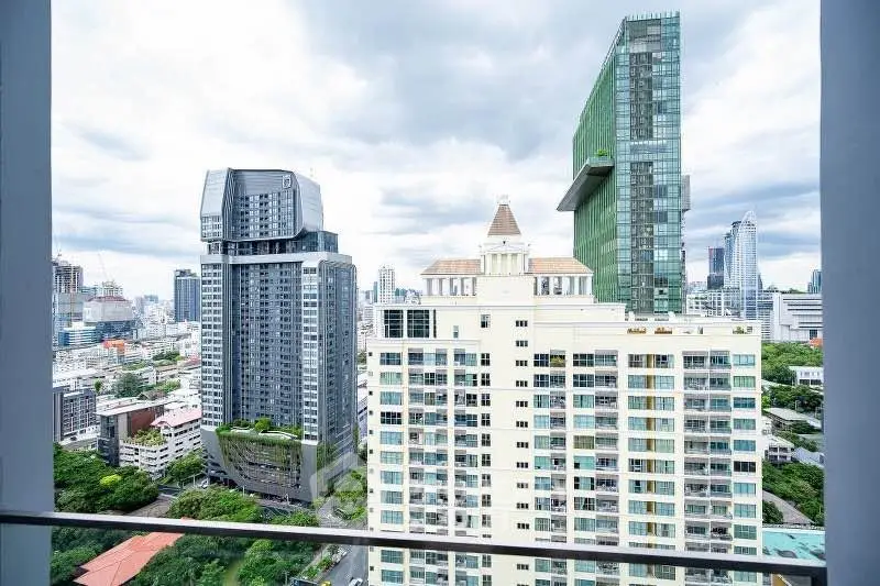 Stunning cityscape view from a high-rise balcony showcasing modern architecture and lush greenery.