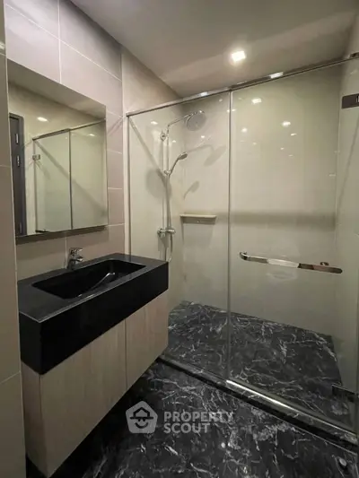 Modern bathroom with sleek black sink and glass shower enclosure