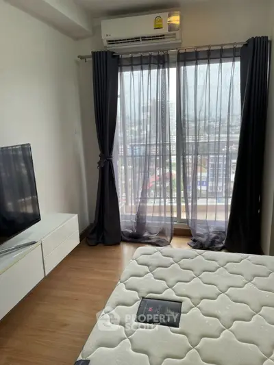 Modern bedroom with city view, featuring sleek furniture and large windows for natural light.