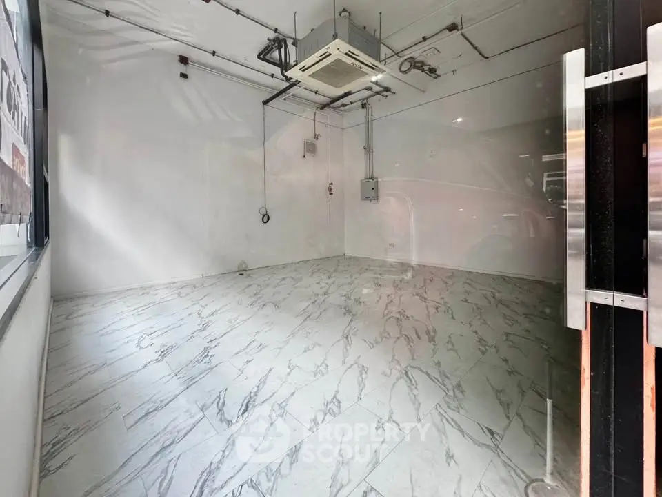 Spacious commercial unit with marble flooring and modern ceiling fixtures, ideal for retail or office space.