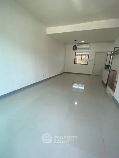 Spacious empty living room with modern tile flooring and large window.