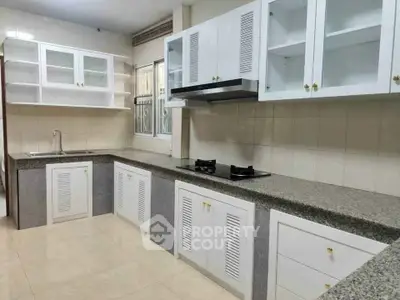 Spacious kitchen with modern cabinetry and gas stove in a well-lit interior.