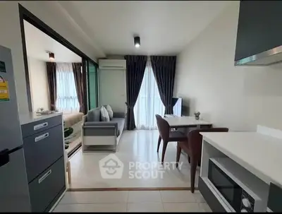Modern open-plan living room with kitchen, featuring sleek furniture and natural light.