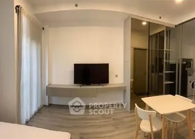 Modern living room with sleek TV setup and dining area in stylish apartment.