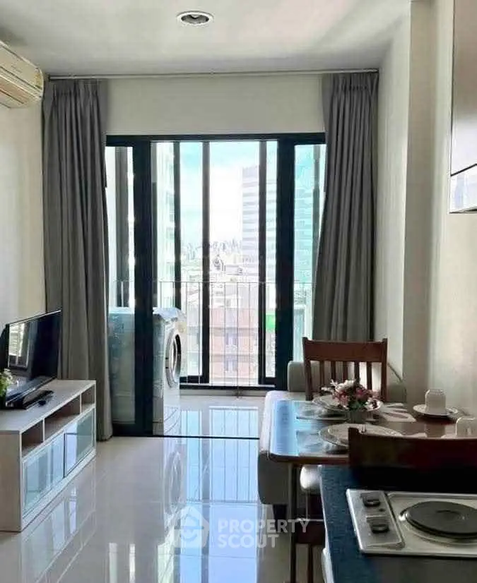 Modern living room with balcony view and compact dining area in urban apartment.