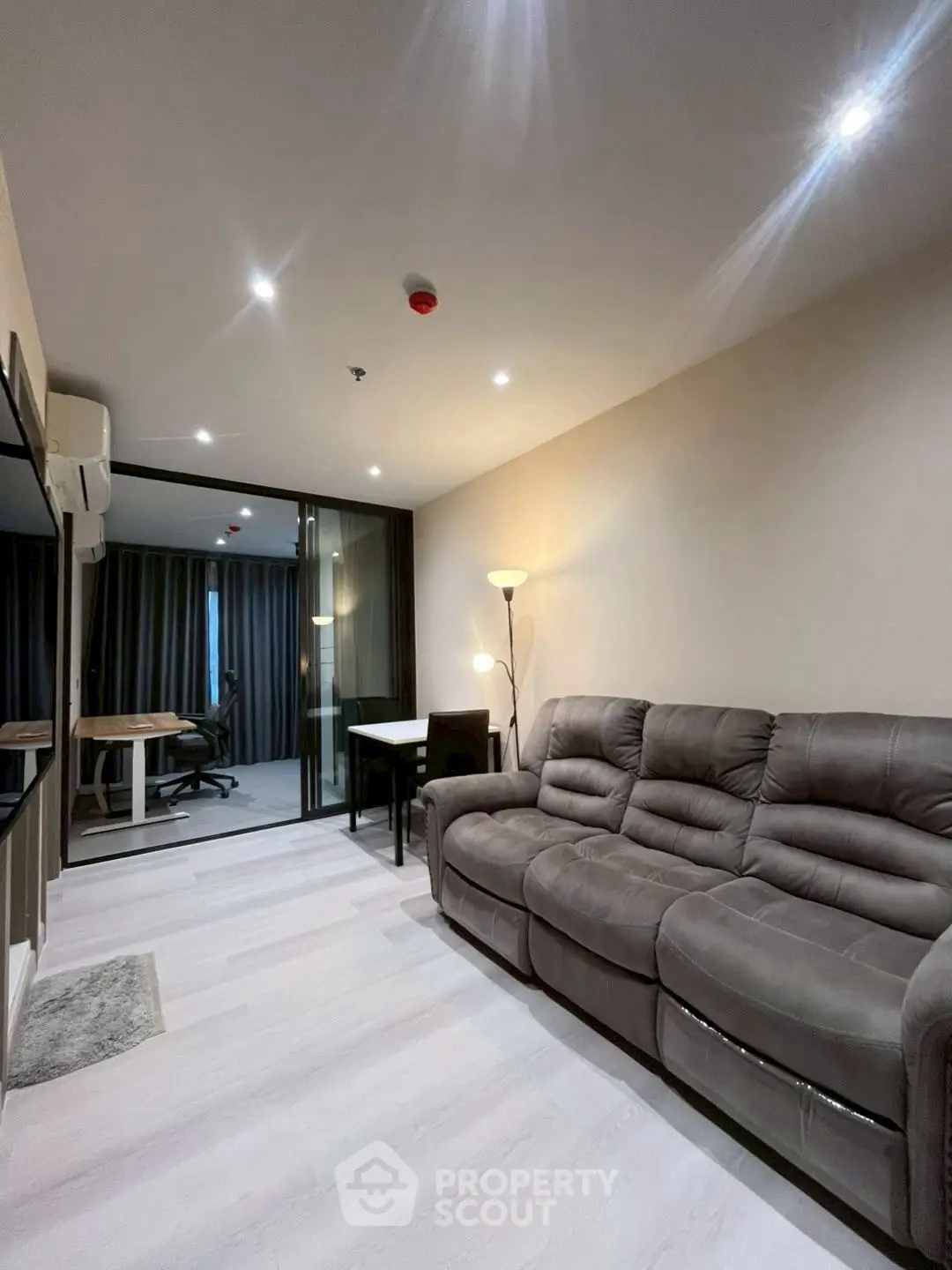 Modern living room with plush sofa and study area in open layout apartment.