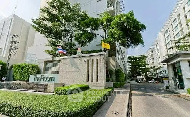 Modern condominium entrance with lush greenery and clear signage.