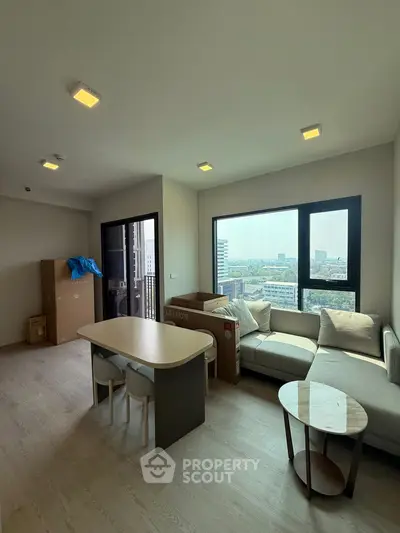 Modern living room with city view, featuring sleek furniture and large windows for natural light.