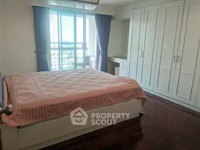 Spacious bedroom with large window and built-in wardrobe in modern apartment
