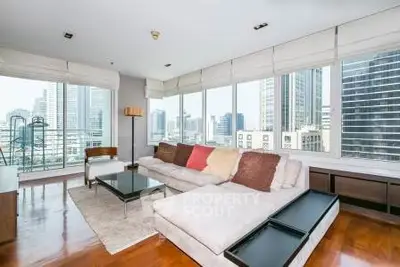 Spacious living room with panoramic city views and modern furnishings in a high-rise apartment.
