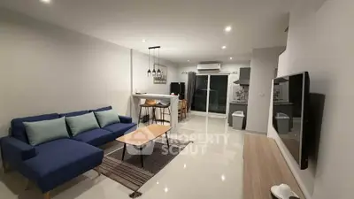 Modern open-plan living room with stylish furniture and kitchen area.