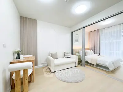 Modern studio apartment with open layout, featuring a cozy living area and elegant bedroom separated by glass doors.