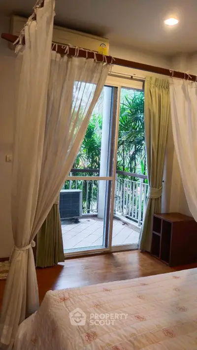 Cozy bedroom with balcony access and lush garden view, perfect for relaxation.