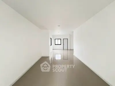 Spacious empty room with glossy tiled floors and white walls, perfect for customization.