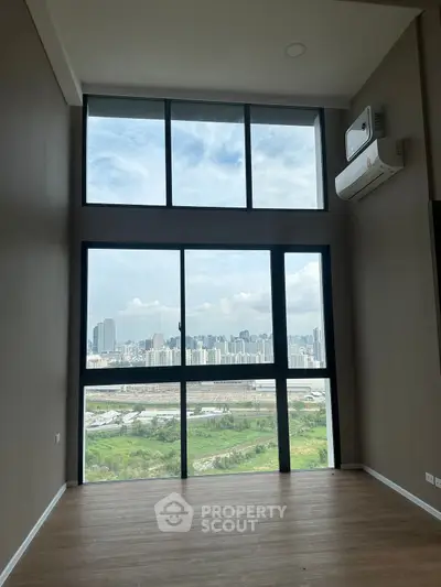 Spacious high-rise apartment with floor-to-ceiling windows offering stunning cityscape views.