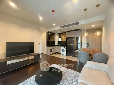 Modern living room with open kitchen, featuring sleek appliances and stylish decor.