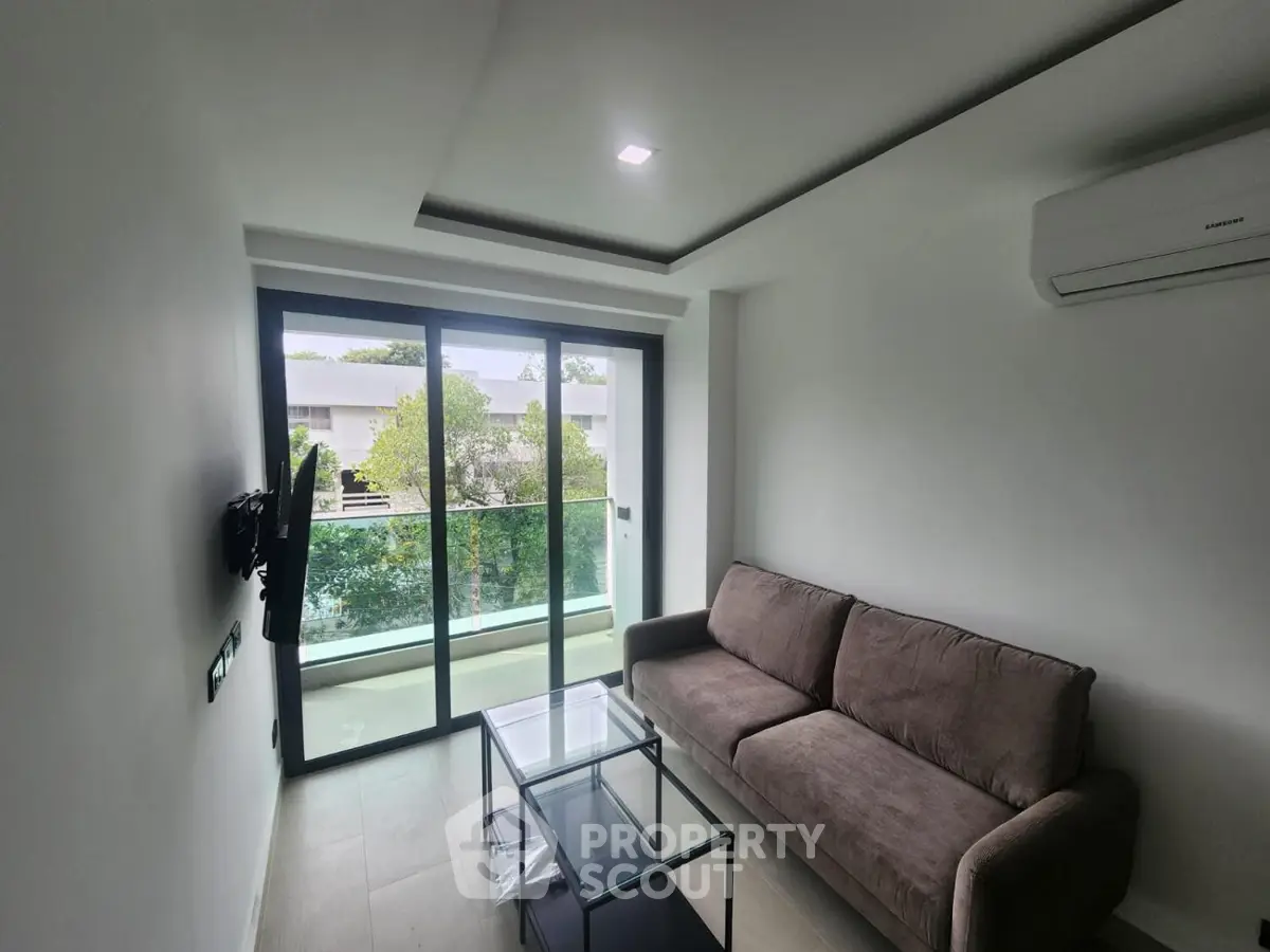 Modern living room with glass doors leading to a balcony, featuring a cozy sofa and sleek design.