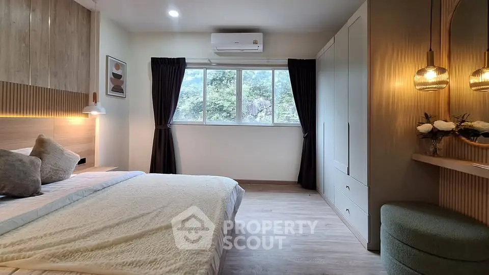 Modern bedroom with stylish decor and large window offering natural light.
