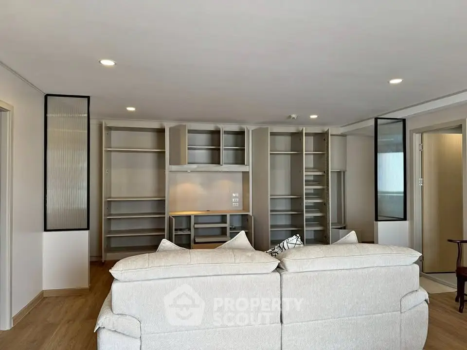 Spacious living room with modern built-in shelving and cozy sofa, perfect for relaxation and entertainment.