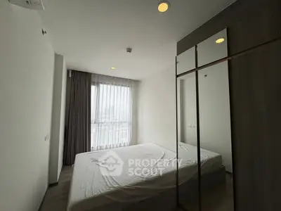 Modern bedroom with large window and mirrored wardrobe in high-rise apartment