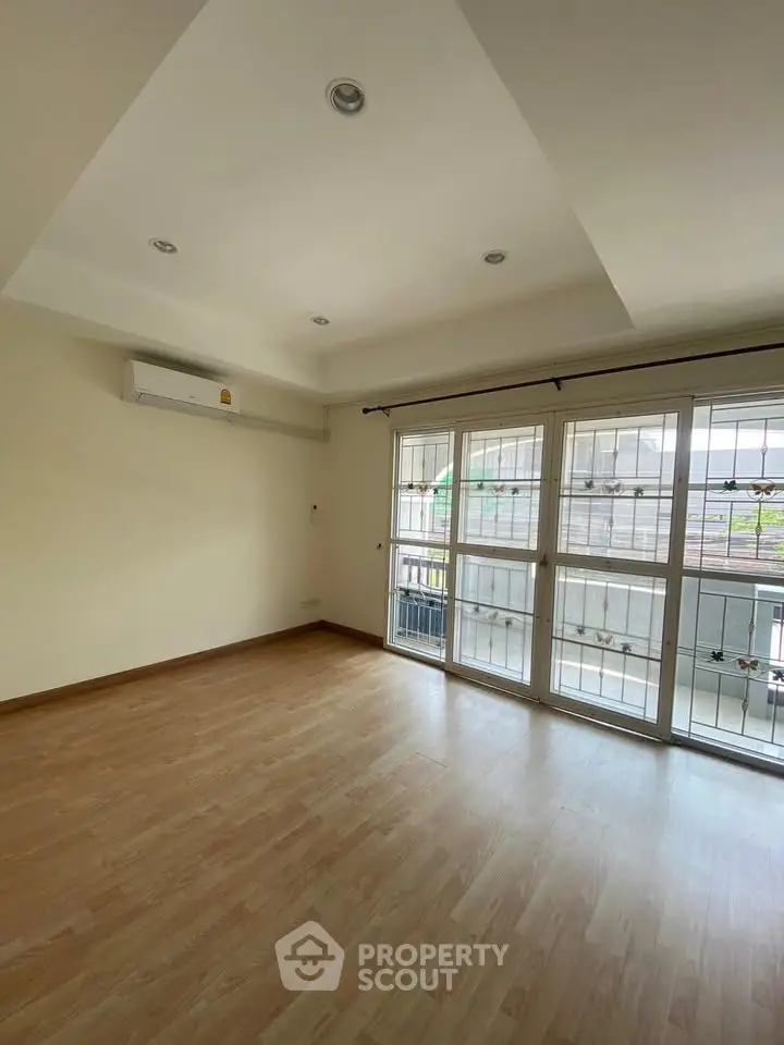 Spacious empty room with wooden flooring and large windows, ideal for customization.