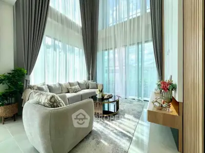 Luxurious living room with high ceilings and elegant decor, featuring large windows and stylish furniture.